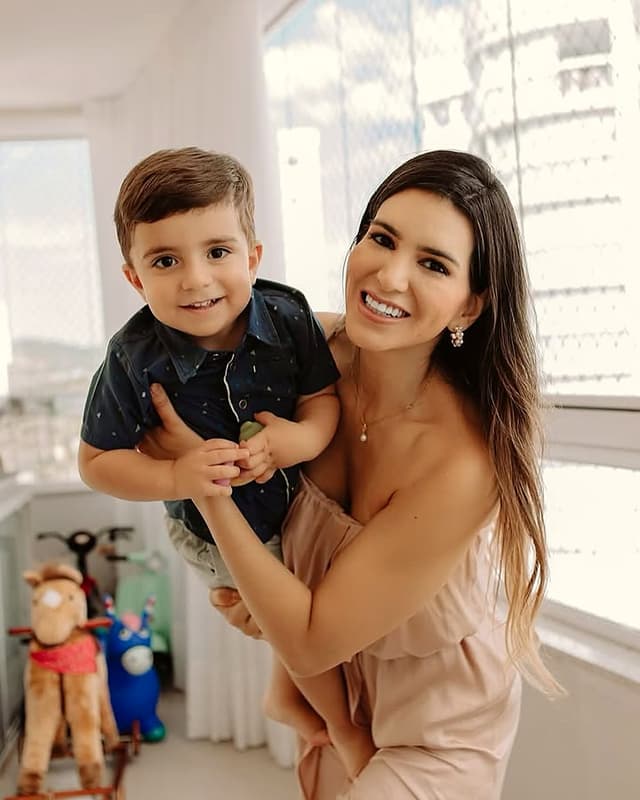 Dra. Raíssa segurando o filho no colo, sorrindo